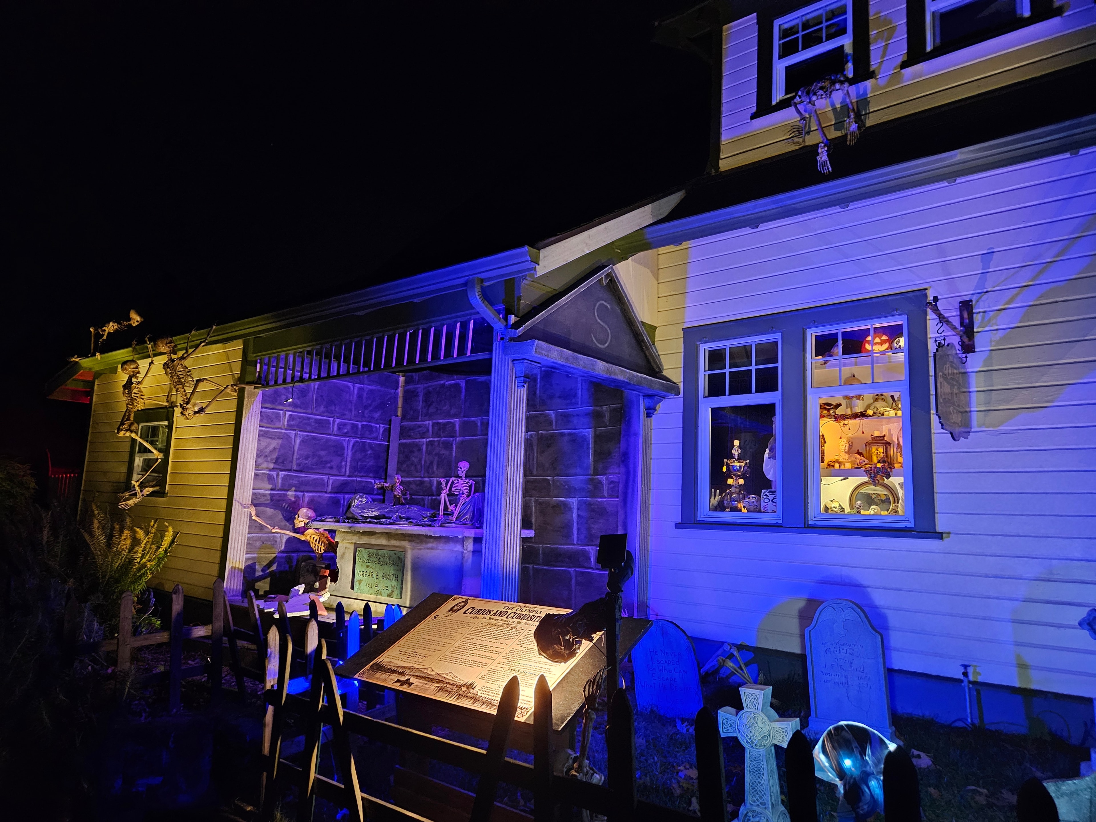 The full Agatha Smith Cemetery haunt — mausoleum facade, gravestones, skeletons scaling the roofline, and display cases glowing through the windows